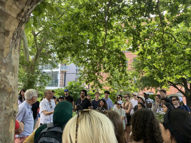 Group of people gathered near a tree and building