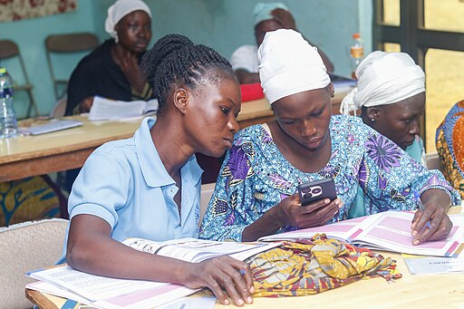 women in Ghana learn to use a cell phone