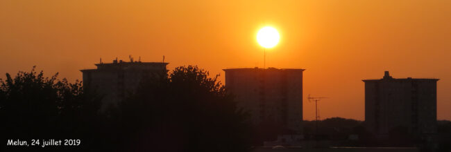 sun over buildings with an orange sky