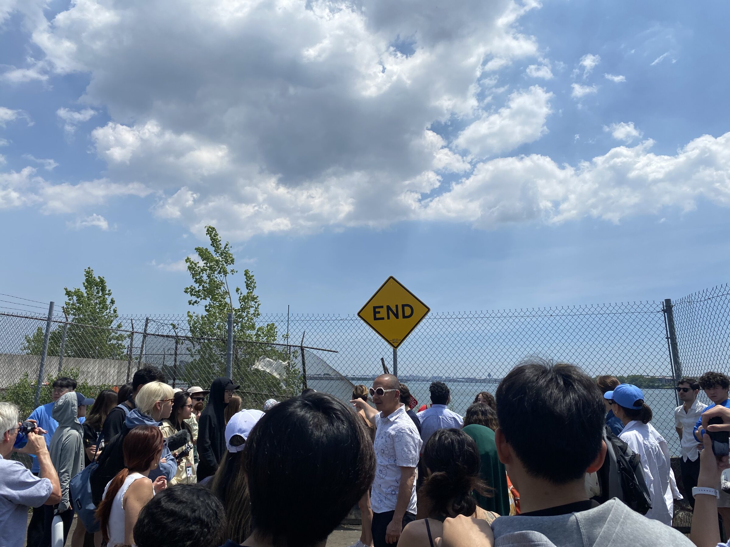 "End" road sign in the background with a group of people listening to a tour guide