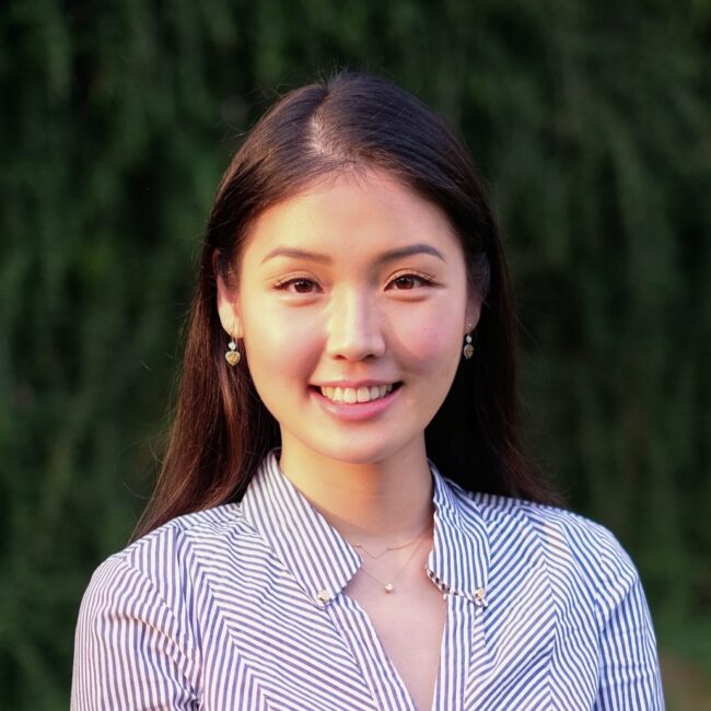 Woman in striped shirt smiles against green backdrop