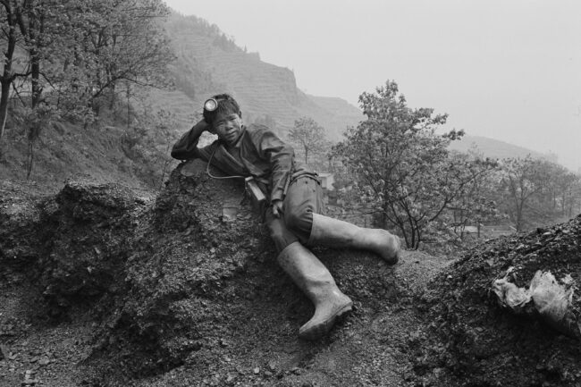 Young coal miner lying on a rock. Yunnan Province, China, 2002. Courtesy of Geng Yunsheng.