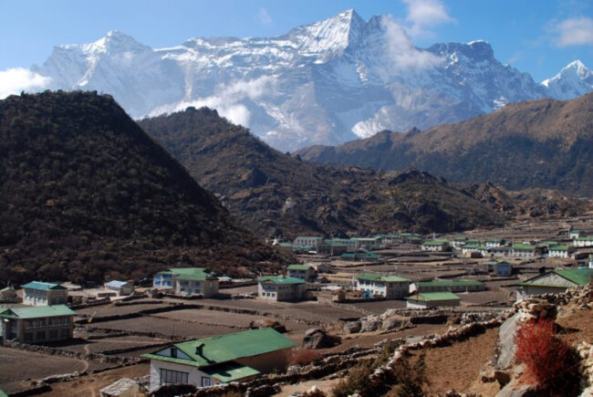 A picture of a small village in Nepal, surrounded by tall mountains 