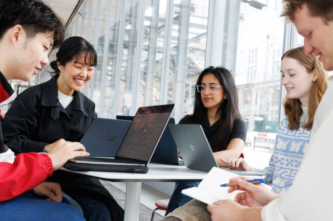 Students sit around a table with their laptops