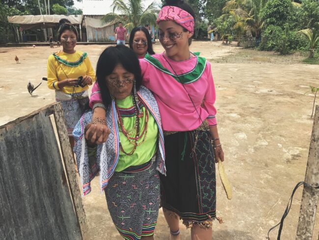 Indigenous women smile arm in arm