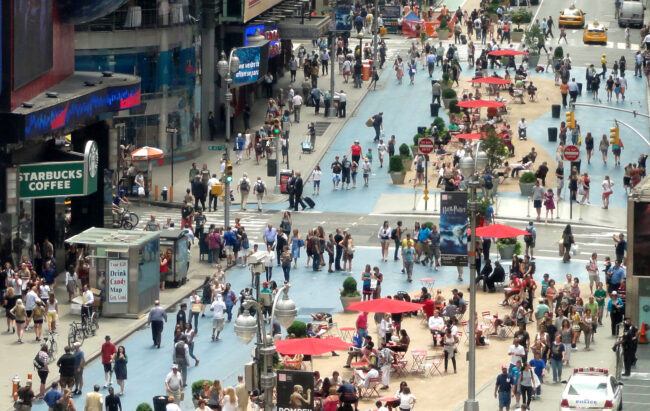 A photo of people walking and sitting on a closed street in Times Square, New York City.