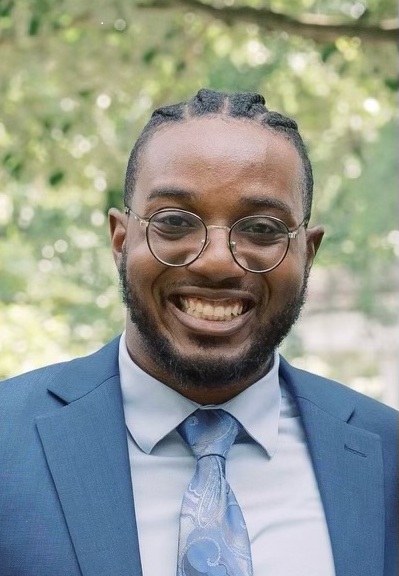 Headshot of man wearing suit jacket and tie