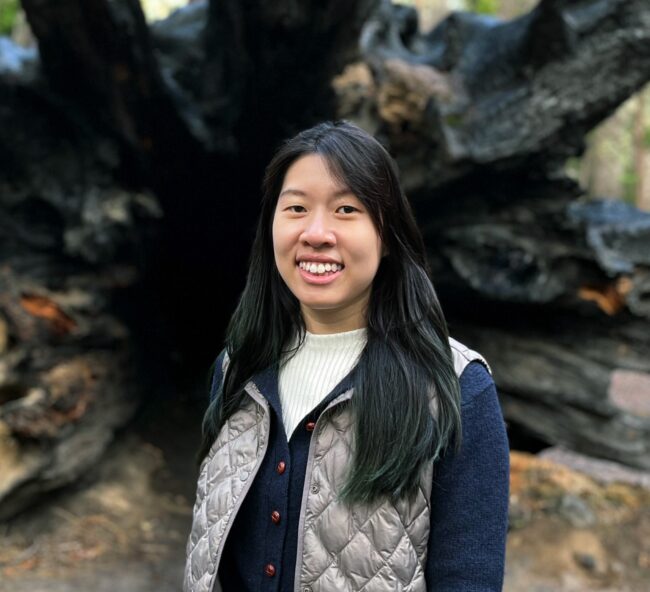 Caroline Juang in front of a large uprooted tree trunk