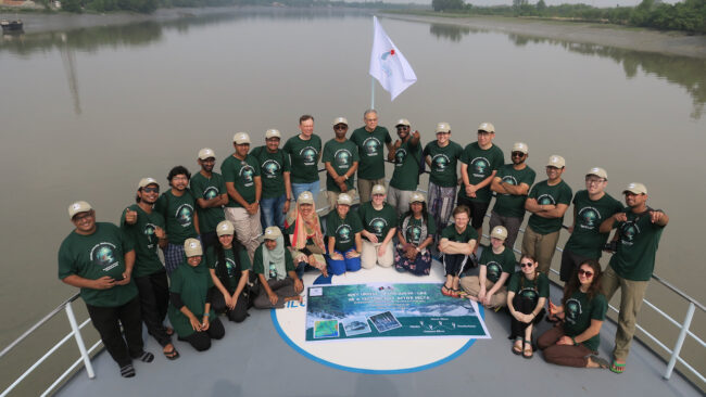 Students and professor in matching shirts on a boat