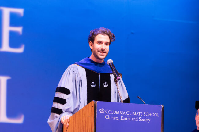 Speaker in graduation robe in front of podium