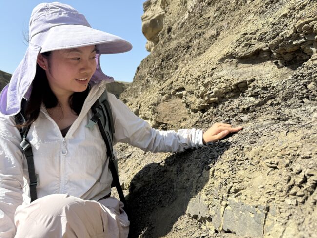 The study’s lead author, Yanan Fang, points to layer of volcanic ash in the sedimentary rock that shows evidence of ancient eruptions, dating back 180 million years.
