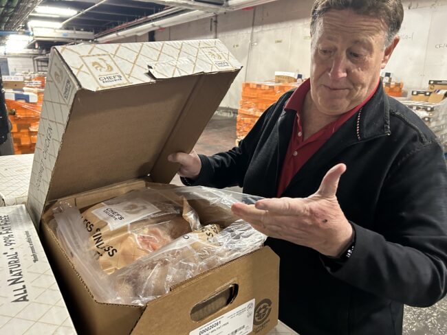 Man showing chicken breasts that are packed and ready to go.