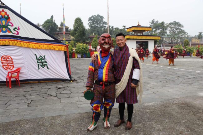 Student Chimi Dorji in Bhutan standing next to person in mask