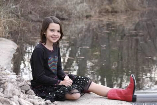 A girl in red boots posing in front of a river